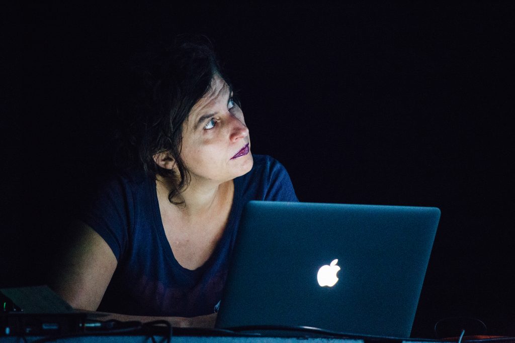 michaela grill performs at mutek festival wearing a blue shirt and an apple computer, audiovisual research into auditory hallucinations, 